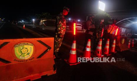 Petugas gabungan berjaga di akses pintu keluar dan masuk kota yang ditutup di Jalur Trans Kalimantan Pahandut Sebrang, Palangkaraya, Kalimantan Tengah, Rabu (13/5/2020) malam. Penyekatan yang dilakukan ke tiga titik pintu akses jalan masuk dan keluar Kota Palangkaraya pada pukul 20