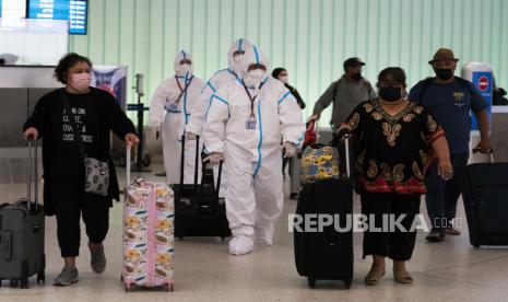 File foto awak pesawat Air China dengan pakaian hazmat berjalan melalui area kedatangan di Bandara Internasional Los Angeles di Los Angeles, Selasa, 30 November 2021. Pemerintahan Joe Biden sedang bersiap untuk melonggarkan pembatasan pengujian Covid-19, khususnya bagi pelancong dari Cina paling cepat pada Jumat (10/3/2023). 