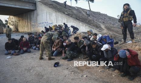 Tentara pemerintah dan sekutunya duduk di tanah saat mereka ditahan oleh pejuang oposisi di jalan antara Homs dan Damaskus, dekat Homs, Suriah, Ahad (8/12/2024). Kekuasaan Partai Baath di Suriah tumbang pada Ahad (8/12/2024). Hal itu ditandai ibu kota Damaskus lepas dari kendali rezim Presiden Bashar al-Assad. Runtuhnya kekuatan pasukan Assad di ibu kota mengakhiri 61 tahun pemerintahan Partai Baath yang penuh kekerasan dan 53 tahun kekuasaan keluarga Assad. 