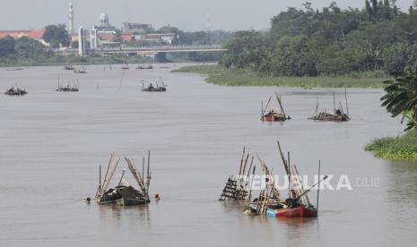 Pekerja menambang pasir menggunakan perahu dengan latar belakang jembatan Brawijaya di aliran sungai Brantas, Kota Kediri, Jawa Timur. Sungai ini pun dipenuhi dengan sampah mikropalstik. 