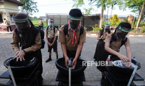 Sejumlah siswa antre mencuci tangan sebelum masuk kelas saat uji coba tatap muka hari pertama di SMP Negeri 2 Klaten, Jawa Tengah, Jumat (9/10/2020). Pemerintah Kabupaten Klaten melakukan uji coba kegiatan belajar mengajar (KBM) pada lima sekolah menengah pertama (SMP) dengan menerapkan protokol kesehatan dengan maksimal 10 siswa per kelas. 