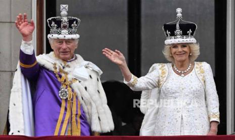 Raja Inggris Charles III (kiri) dan Ratu Camilla melambaikan tangan dari balkon Istana Buckingham usai penobatan mereka di London, Inggris, Sabtu (6/5/2023).