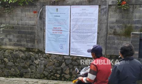 Sebuah tulisan himbauan wajib lapor untuk pendatang dari zona merah Covid-19 dipasang di gerbang masuk salah satu gang di daearah Langensari, Kecamatan Lembang, Kabupaten Bandung Barat, Ahad (5/4). Mulai banyaknya pendatang dan pemudik dari zona merah Corona atau Covid-19 ke berbagai daerah di Jawa Barat, lingkungan setempat dari RT dan RW telah menerapkan wajib lapor dan isolasi diri selama 14 hari