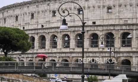 Orang-orang melewati Colosseum pada hari hujan di Roma, Italia, 31 Agustus 2020. Italia merupakan negara Eropa pertama yang dilanda wabah Covid-19.