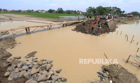 Warga bersama petugas gabungan bergotong royong memperbaiki tanggul sungai Cipunagara yang jebol di desa Bongas, Pamanukan, Subang, Jawa Barat, Rabu (24/2/2021). Puluhan warga dibantu personel TNI, BPBD dan LSM bergotong royong memperbaiki tanggul jebol yang menyebabkan banjir di Pamanukan dengan material yang didatangkan oleh dinas PUPR dan BBWS Citarum. 