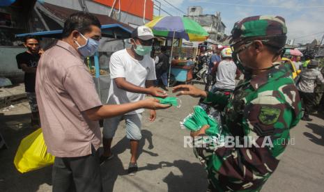 Prajurit TNI AD membagikan masker kepada warga di pasar besar Palangkaraya, Kalimantan Tengah, Kamis (16/4/2020). Tim Gugus Tugas Penanganan COVID-19 setempat membagikan 10 ribu masker gratis dan sosialisasi kepada warga sebagai upaya pemerintah setempat mencegah penyebaran COVID-19