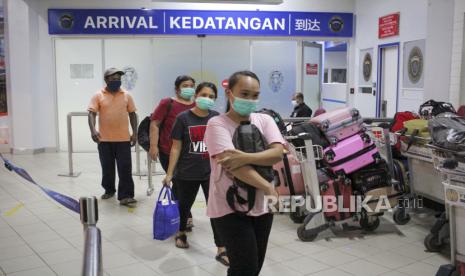 Pekerja Migran Indonesia (PMI) berjalan keluar dari pintu  kedatangan usai pemeriksaan dokumen perjalanan di Pelabuhan Internasional Batam Centre, Batam, Kepulauan Riau, Senin (3/01/2022). Satgas Penanganan COVID-19 memperketat pengawasan pintu masuk PMI melalui jalur laut seiring dengan merebaknya varian Omicron dan adanya dugaan penggunaan surat keterangan hasil PCR palsu yang dibawa oleh PMI. 