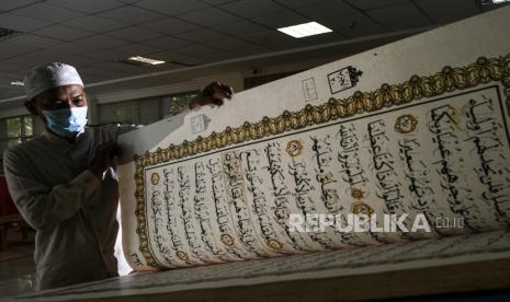 Petugas merawat Al Quran raksasa di Perpustakaan Jakarta Islamic Centre (JIC), Jakarta Utara, Selasa (20/4/2021). Al Quran yang berukuran 100 x 50 centimeter dengan berat sekitar 100 kilogram tersebut dibersihkan setiap tiga hari sekali meskipun perpustakaan masih belum dibuka untuk umum karena masih dalam pandemi COVID-19. 