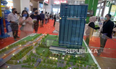 Pengunjung melintas di dekat maket hunian yang dipamerkan dalam pameran properti. ilustrasi