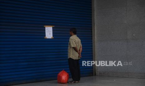 Warga membaca pengumuman penutupan Pasar Tanah Abang, Jakarta, Jumat (27/3). Dalam rangka pencegahan dan menekan angka penularan virus Corona (COVID-19), Perumda Pasar Jaya menutup sementara Pasar Tanah Abang Blok A, B dan F mulai 27 Maret hingga 5 April 2020