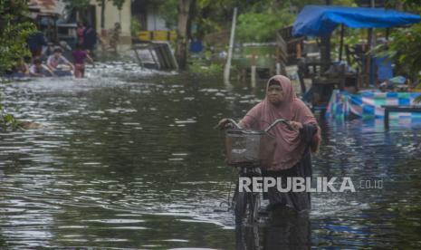 Warga menuntun sepedanya melintasi banjir yang merendam Jalan Prona di Banjarmasin, Kalimantan Selatan, Kamis (14/1/2021). Berdasarkan data yang telah dihimpun Badan Penanggulangan Bencana Daerah (BPBD) Provinsi Kalimantan Selatan dari tanggal 1 hingga 14 Januri, sebanyak 19.452 rumah terendam banjir di sejumlah wilayah di Kalimantan Selatan. 