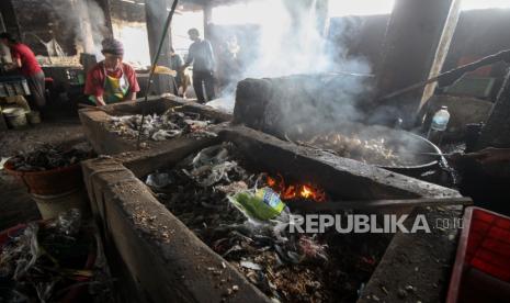 Pekerja menggoreng tahu di salah satu pabrik tahu yang menggunakan sampah plastik sebagai bahan bakar di Tropodo, Krian, Sidoarjo, Jawa Timur, Senin (30/5/2022). Pabrik tahu di wilayah tersebut menggunakan sampah plastik dan spon karet sebagai bahan bakar karena harganya yang murah meski asap hasil pembakaran sampah plastik telah mencemari udara. 