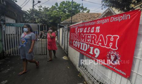 Warga melintas di dekat spanduk pemberitahuan zona merah saat pemberlakuan pembatasan kegiatan masyarakat (PPKM) skala mikro hari pertama di kawasan Senen, Jakarta, Selasa (9/2). Pemerintah mulai menerapkan PPKM skala mikro mulai 9-22 Februari 2021 untuk tujuh provinsi yakni DKI Jakarta, Jawa Barat, Banten, Jawa Tengah, Yogyakarta, Jawa Timur, dan Bali. Republika/Putra M. Akbar