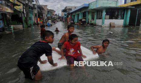 Anak-anak bermain saat banjir rob di kawasan Muara Angke Jakarta, Selasa (14/1/2025). 