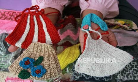 Seorang perajin menunjukan masker rajut berlapis kain hasil karyanya di Sentra Rajut Tangsel, Pamulang, Tangerang Selatan, Banten, Senin (12/10/2020). Dalam satu hari UMKM ini mampu menyelesaikan 5 buah masker rajut berlapis kain, yang dijual secara daring dengan harga Rp.30 ribu satu maskernya. 