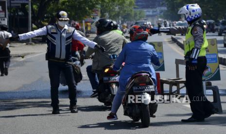 Petugas gabungan berusaha memberhentikan seorang pengendara yang tidak menggunakan masker saat uji coba penerapan Pembatasan Sosial Berskala Besar (PSBB) di Makassar, Sulawesi Selatan, Selasa (21/4/2020). Pemerintah kota Makassar melakukan uji coba penerapan PSBB selama tiga hari agar penerapan PSBB yang akan dilaksanakan pada (24/4/2020) dapat berjalan efektif  dalam percepatan penanganan COVID-19