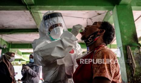 Petugas mengambil sampel cairan dari hidung dan tenggorokan pedagang saat mengikuti swab test 