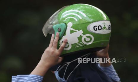 Seorang wanita memegang helm Gojek setelah tiba di sebuah stasiun di Jakarta, Indonesia, Senin, 17 Mei 2021. ilustrasi