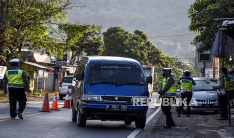 Petugas gabungan melakukan penyekatan kendaraan dengan plat nomor dari luar Garut di posko penyekatan larangan mudik di Jalan Nanggeleng, Limbangan, Kabupaten Garut, Ahad (9/5). Memasuki hari keempat penerapan larangan mudik Lebaran 2021, petugas gabungan di posko penyekatan larangan mudik Limbangan telah memutarbalikan sedikitnya 150 kendaraan berplat luar kota dari arah Bandung menuju Garut dan Tasikmalaya karena tidak memiliki surat kesehatan serta ijin perjalanan. Foto: Republika/Abdan Syakura