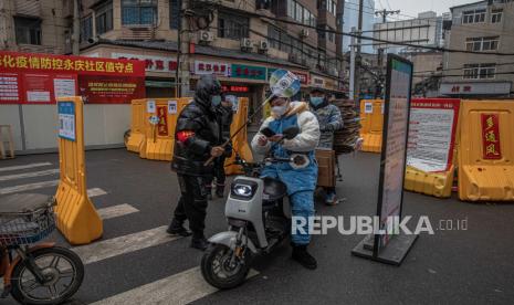 China Tangkap Tersangka Pembuat Vaksin Covid-19 Palsu. Seorang relawan keamanan publik (kiri) yang berdiri di samping pagar keamanan memeriksa kode kesehatan seorang pria untuk mencegah penyebaran penyakit virus corona (Covid-19), di kawasan pemukiman Wuhan, China, 22 Januari 2021. Hari 23 Januari 2021 menandai peringatan satu tahun dimulainya penguncian 76 hari yang ketat di kota Wuhan di China tempat virus korona pertama kali ditemukan sebelum menyebar ke seluruh dunia menjadi pandemi global yang mematikan.