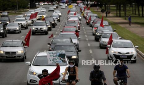  Seorang demonstran membawa poster bertuliskan dalam bahasa Portugis bertuliskan Vaksinasi Menyelamatkan Nyawa di dalam karavan sebagai protes terhadap tanggapan pemerintah dalam memerangi Covid-19 dan menuntut pemakzulan Presiden Brasil Jair Bolsonaro, di Brasilia, Brasil, Sabtu, 21 Februari, 2021. Demonstrasi serupa berulang pada Sabtu (19/6).