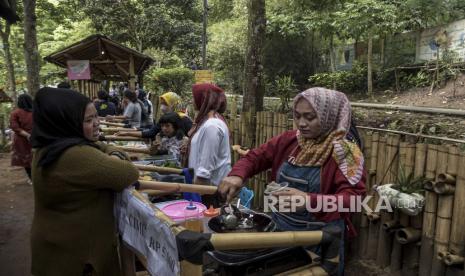 Warga membeli jajanan tradisional yang dijual di Kampoeng Tjibarani di kawasan bantaran Sungai Cikapundung, Cidadap, Kota Bandung, Ahad (15/1/2023). Selain menjadi kawasan wisata alternatif di Kota Bandung, kawasan bantaran Sungai Cikapundung tersebut menjadi salah satu contoh upaya menjaga kelestarian alam khususnya sungai.