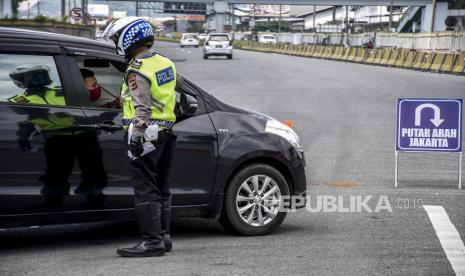 Petugas kepolisian mengarahkan kendaraan untuk memutar balik di Gerbang Keluar Tol Cileunyi, Kabupaten Bandung, Sabtu (23/5). Penindakan berupa pemeriksaan identitas, surat jalan hingga mengarahkan kendaraan untuk memutar balik tersebut ditujukan untuk penyekatan pemudik yang akan menuju jalur selatan dan jalur tengah guna memutus mata rantai penyebaran Covid-19