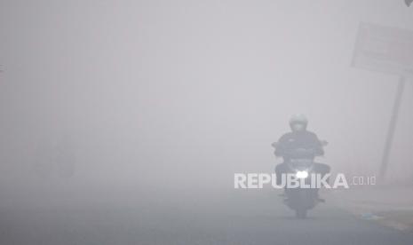 Pengendara melintas di Jalan Pendidkan yang tertutup kabut asap di Jakabaring, Palembang, Sumatera Selatam, Sabtu (7/10/2023). 