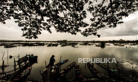 Seorang warga melihat perahu nelayan yang ditambatkan di kawasan waduk yang tercemar limbah mercuri  (ilustrasi)