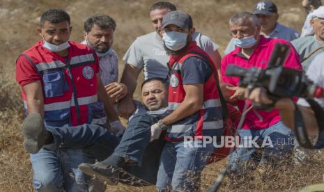  Paramedis mengevakuasi seorang pria Palestina setelah bentrok dengan polisi perbatasan Israel ketika mencoba mencapai kebun zaitun untuk panen, di desa Burqa Tepi Barat, Timur Ramallah, Jumat, 16 Oktober 2020. Ketika panen zaitun dimulai, pemukim Israel melakukan serangan ke petani Palestina.