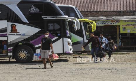 Sejumlah calon penumpang melintas di area parkir bus AKAP di terminal bayangan Pondok Pinang, Jakarta Selatan. Setiap penumpang kini diwajibkan menunjukkan surat sudah divaksin.