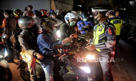 Petugas gabungan memeriksa surat keterangan negatif Covid-19 pengedara motor saat arus balik lebaran.