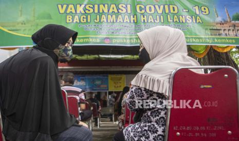 Sejumlah jemaah calon haji berbincang saat antre mengikuti vaksinasi COVID-19 dosis pertama di Puskesmas Merdeka, Palembang, Sumatera Selatan, Kamis (25/3).