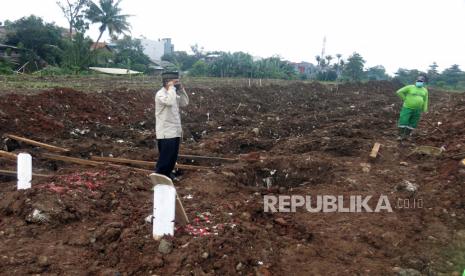 Pihak keluarga korban mengumandangkan azan setelah penguburan jenazah korban COVID-19 di TPU Srengseng Sawah Dua, Jagakarsa, Jakarta Selatan, Selasa, (2/2/2021). Kepala Pusat Data dan Informasi (Kapusdatin) Dinas Pertamanan dan Pemakaman DKI Jakarta Ivan Murcahyo menyatakan TPU Srengseng Sawah dua telah mulai menerima pemakaman jenazah COVID-19 dengan kapasitas 1.020 petak. 