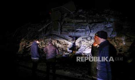 Sejumlah orang menunggu saat personel darurat mencari korban di lokasi bangunan yang runtuh setelah gempa bumi di distrik Iskenderun di Hatay, Turki, Senin (6/2/2023). Mabes Polri akan mengirim bantuan personel untuk membantu korban gempa di Turki.