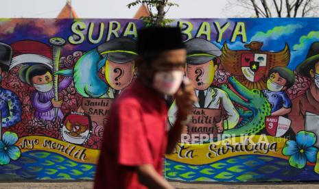 Warga melintas di dekat tembok bermural di kawasan Dupak Rukun, Surabaya, Jawa Timur, Rabu (7/10/2020). Mural tersebut sebagai bentuk sosialisasi serta ajakan kepada masyarakat untuk menggunakan hak pilihnya pada pemilihan Wali Kota dan Wakil Wali Kota Surabaya tahun 2020. 