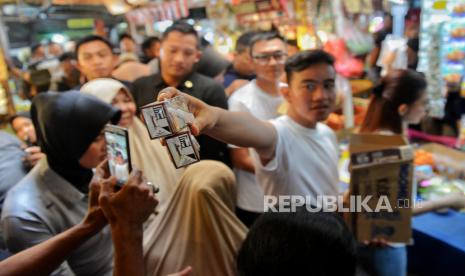 Cawapres nomor urut dua Gibran Rakabuming Raka membagikan susu kepada pengunjung di Pasar Rawasari, Cempaka Putih, Jakarta Pusat, Ahad (3/12/2023). 