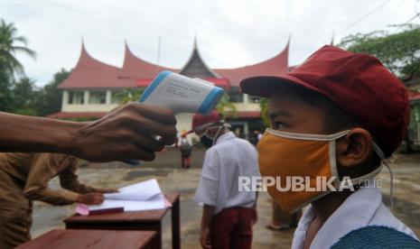 Guru memeriksa suhu tubuh murid saat hari pertana masuk sekolah di SDN 11 Marunggi, Pariaman, Sumatera Barat, Senin (13/7/2020). Kota Pariaman bersama Kabupaten Pesisir Selatan, Kota Sawahlunto dan Kabupaten Pasaman Barat merupakan empat daerah di zona hijau di Sumatera Barat yang sudah memulai aktivitas belajar-mengajar di sekolah dengan pola tatap muka langsung dan menerapkan protokol kesehatan Covid-19. (ilustrasi) 