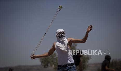  Seorang pengunjuk rasa Palestina menggunakan ketapel untuk melemparkan batu selama protes terhadap pos terdepan pemukiman Yahudi Tepi Barat Eviatar yang dengan cepat didirikan bulan lalu, di desa Palestina Beita, dekat kota Nablus, Tepi Barat, Jumat, 25 Juni 2021.