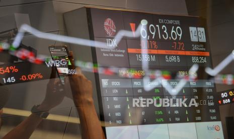 Karyawan beraktivitas di dekat layar yang menampilkan indeks harga saham gabungan (IHSG).