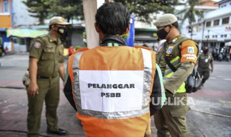 Warga yang melanggar aturan pemberlakuan Pembatasan Sosial Berskala Besar (PSBB) mengenakan rompi bertuliskan Pelanggar PSBB saat terjaring Operasi Tertib Masker di kawasan Kota Tua, Jakarta, Ahad (27/9/2020).