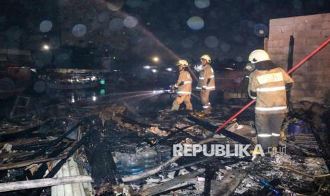 Sejumlah petugas melakukan pendinginan saat memadamkan kebakaran di Jalan Cakung Drain, Cilincing, Jakarta, Rabu (1/1/2025) dini hari. Kebakaran yang diduga dipicu karena ledakan petasan tersebut menyebabkan enam rumah dan perahu ludes terbakar. 