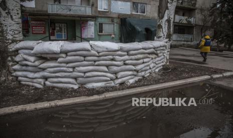 Seorang jurnalis melewati tempat perlindungan di dekat sebuah rumah apartemen setelah penembakan oleh separatis pro-Rusia di desa Novoluhanske, wilayah Luhansk, Ukraina, Sabtu, 19 Februari 2022.