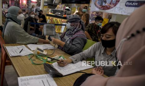 Petugas kesehatan memeriksa tekanan darah warga saat kegiatan pemeriksaan deteksi dini penyakit tidak menular (PTM) di salah satu pusat perbelanjaan di Jalan Purwakarta, Antapani, Kota Bandung, Jumat (27/5/2022). Dinas Kesehatan Kota Bandung menggelar pemeriksaan deteksi dini penyakit tidak menular (PTM) berupa pemeriksaan tekanan darah, gula darah, skrining kejiwaan hingga vaksin Covid-19 bagi masyarakat secara gratis dalam rangka memperingati Hari Hipertensi Sedunia. Foto: Republika/Abdan Syakura