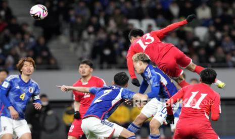 Pemain Korea Utara Ri Il-song (kanan atas) dan pemain Jepang Ritsu Doan (tengah bawah) berebut bola selama pertandingan babak kualifikasi putaran kedua Piala Dunia FIFA 2026.AFC 2027.