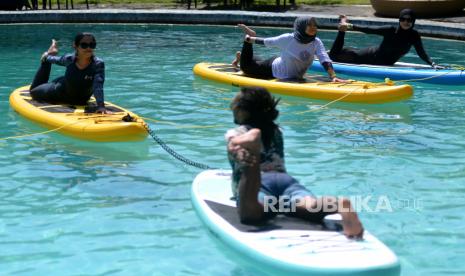 Peserta melakukan gerakan yoga di atas papan dayung saat mengikuti Unique Bali Festival (UBF) 2022 di kawasan Sanur, Denpasar, Bali, Ahad (3/7/2022). Wisata healing yang melibatkan aktivitas yoga dan meditasi pun kini diminati generasi milenial.