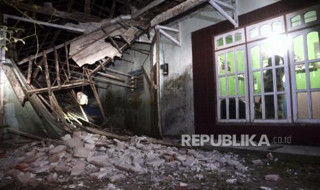 Seorang wanita mengamati bagian rumahnya yang rusak akibat gempa bumi di Malang, Jawa Timur, Indonesia, Sabtu, 10 April 2021. 