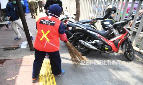 Seorang warga yang terjaring razia penindakan pelanggaran aturan Pembatasan Sosial Berskala Besar (PSBB) oleh Satpol PP menjalani hukuman dengan cara membersihkan sampah di Tanah Abang, Jakarta, Rabu (13/5/2020). Pemprov DKI Jakarta mulai memberlakukan sanksi sosial terhadap pelanggar PSBB yaitu dengan memakaikan rompi bertuliskan pelanggar PSBB saat mereka membersihkan fasilitas umum