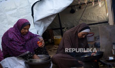 Pengungsi Palestina menyiapkan santapan berbuka puasa di hari pertama bulan suci Ramadhan di tenda darurat kawasan Muwasi, Gaza selatan, Selasa (12/3/2024). 