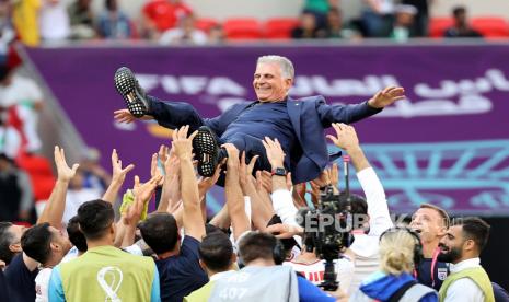 Para pemain Iran melambungkan pelatih mereka Carlos Queiroz seusai kemenangan 2-0 atas Wales pada laga lanjutan Grup B Piala Dunia 2022, Jumat (25/11/2022).